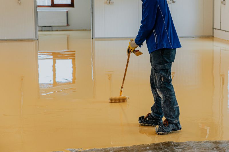 worker levelling epoxy coating over concrete